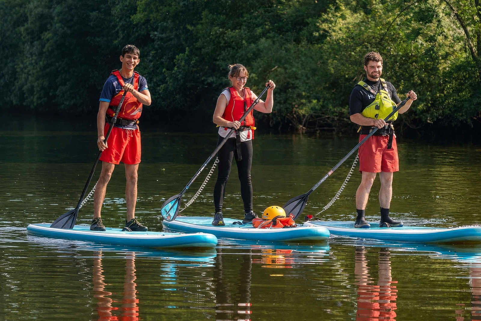 Three paddlers stand-up paddleboarding on the River Wye